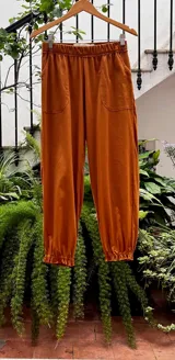 Pantalón tipo babucha color naranja, con cintura y puños elastizados, bolsillos delanteros y confeccionado en algodón.