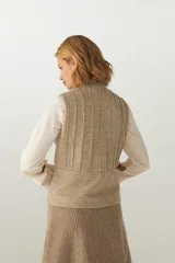 Chaleco color crema con cuello alto y cierre frontal con cremallera. Diseño con alforzas verticales en la parte superior delantera y trasera.