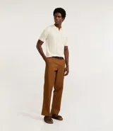 Camisa de punto color crema, con cuello polo y cierre frontal parcial con cremallera, de manga corta y diseño texturizado con perforaciones verticales.