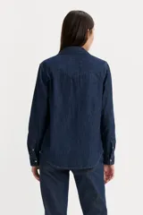 Camisa de denim azul con bolsillos en el pecho con solapas puntiagudas y cierre con broches a presión.