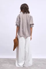 Camisa marrón a rayas verticales blancas y marrones, de corte amplio y mangas cortas.