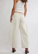 Pantalón de jean color crema, de corte relajado, piernas anchas y tiro medio. Tiene una silueta distinta y un largo hasta los tobillos.