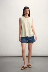 Blusa color crema sin mangas, de lino, con cuello redondo y corte recto.