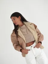 Campera de cuero vacuno color marrón con solapa de corderito negro y costuras a mano.