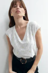 Blusa negra con bordado de flores blancas, escote en V y mangas cortas.