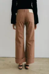 Pantalón de jean azul oscuro con corte acampanado, tiro medio y dobladillo en el ruedo. Presenta costuras marcadas en el frente y estampado abstracto en tonos grises y blancos en el interior del dobladillo.