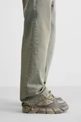 Zapatillas bajas color gris claro con cordones y suela gruesa con diseño irregular.