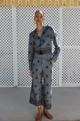 Blusa azul con bordados negros, cuello redondo con escote en pico y cordones ajustables terminados en borlas.