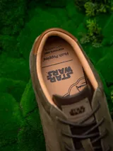 Zapatillas urbanas de cuero color verde oliva con detalles en marrón y negro. Presentan el logo de Star Wars en el talón y el rostro de Yoda grabado en el lateral.