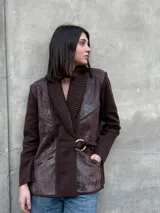 Chaqueta marrón de lana tejida con paneles de cuero texturizado, cuello acanalado, cierre con hebilla dorada y bolsillos laterales.