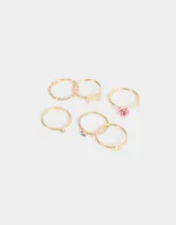 Set de seis anillos dorados de metal con diferentes diseños: texturado, con corazón, strass, mariposa y flor.