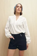 Short de jean negro de tiro alto con detalle de doble botón metálico en la cintura, bolsillos delanteros y traseros.