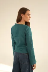 Blusa blanca de lino con escote en V cruzado, mangas largas y lazo en la cintura.