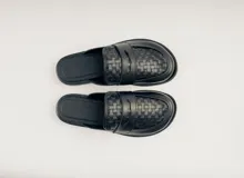 Mocasín mule de cuero negro con capellada tejida.