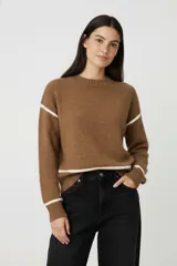 Sweater acrílico color marrón, de corte holgado, cuello redondo y manga larga. Presenta rayas blancas en los hombros y en el dobladillo.