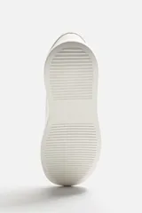 Zapatillas deportivas blancas, de estilo minimalista, con cordones y suela gruesa.