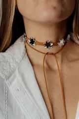 Gargantilla marrón de cuero con dije de estrellas plateadas.
