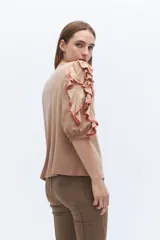 Remera color beige con mangas cortas y volados con borde naranja.