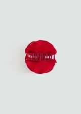 Pinza para el pelo color rojo con forma de labios y textura acanalada.