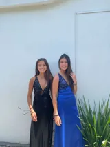 Vestido largo con escote en V, estampado en tonos rojizos y rosados, con un patrón ondulado. Presenta cut-outs laterales bajo el busto y breteles finos que se cruzan en la espalda.