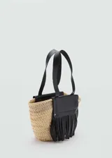 Bolso tipo tote de fibra natural color beige con aplique de cuero negro con flecos y doble asa corta.
