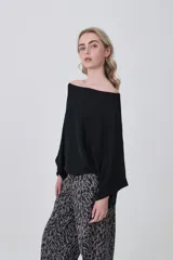 Sweater holgado de tejido ligero, color beige claro, con escote asimétrico que deja un hombro al descubierto.