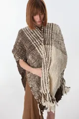 Ruana artesanal tejida en telar con lana hilada a rueca por tejedoras rurales de Uruguay. Diseño con patrón a cuadros en tonos marrón y crudo, con flecos en los extremos.