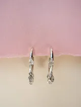 Aros tipo argolla dorados con siete circonias transparentes colgantes.