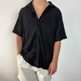 Camisa negra tejida con cuello solapa, manga corta y corte oversize.