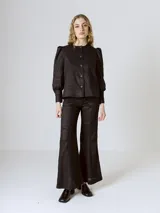 Pantalón negro de lino con corte flare, tiro medio y costuras verticales al frente.