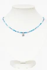 Collar corto de cristalitos facetados en tonos de azul y celeste, con pelotitas de acero y dije de estrella de acero.