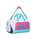 Bolso deportivo tipo duffel bag, predominantemente blanco, con detalles en rosa vibrante, azul celeste y negro. Presenta el texto "Miami" en cursiva sobre un panel rosa en el centro. Cuenta con asas de mano y correa ajustable para hombro.