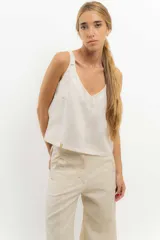Top sin mangas color beige claro, con escote en V pronunciado y breteles finos. Presenta un calce recto y holgado.