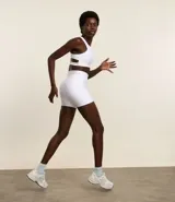 Top deportivo blanco con escote halter y tiras diferenciadas en la espalda. Confeccionado en microfibra acanalada y levemente brillante.