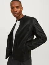 Chaqueta biker negra de cuero sintético con cierre de cremallera, cuello mao con botón a presión, detalles acolchados en los hombros, bolsillos laterales con cremallera, puños con cremallera y forro de poliéster reciclado.