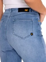 Pantalón de jean celeste claro con rotura en la rodilla, corte recto y diseño de cinco bolsillos.
