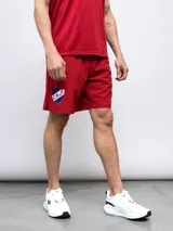 Bermuda deportiva roja de entrenamiento, con escudo del Club Nacional de Football estampado en la pierna izquierda.