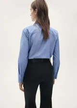 Camisa celeste de manga larga con puños abotonados, diseño recto, cierre delantero de botones a presión, cuello camisero, costuras decorativas, tachuelas decorativas y bordado decorativo.