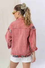 Campera de jean oversize, color rojo desgastado, con aplicaciones de tapicería multicolor de estilo étnico en hombros y ruedo, y terminaciones desflecadas.