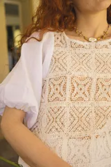 Blusa blanca con cuerpo de encaje de crochet cuadrillé y mangas abuchonadas de lino.