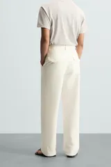 Pantalón de vestir blanco, corte recto (straight fit), con cierre frontal de cremallera y botón, bolsillos delanteros y bolsillos traseros con solapa y botón.