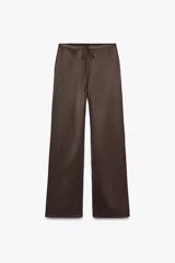 Pantalón de tiro alto confeccionado en tejido satinado color marrón chocolate, con cintura ajustable con lazada y pernera recta.