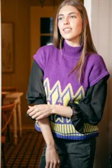 Chaleco de punto morado con cuello alto y diseño geométrico amarillo y azul.