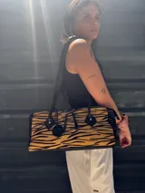 Cartera tipo baguette con estampado animal print blanco y negro, detalles en cuero negro y doble cierre superior.