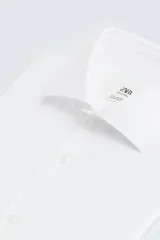 Camisa blanca de manga larga con cuello italiano abierto y puños abotonados. Presenta un corte slim fit y cierre frontal de botonadura.