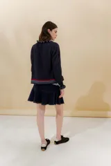 Saco tejido azul marino con cuello redondo, cierre frontal con botones y detalle de volados en cuello y puños.