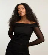Blusa negra con escote hombro a hombro y mangas largas de tul transparente.