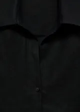 Camisa blanca de lino, de corte oversize, manga larga con puños abotonados, cuello camisero y cierre frontal con botones.