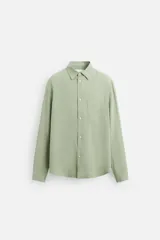 Camisa verde claro de corte relaxed fit confeccionada en tejido con mezcla de modal. Tiene cuello italiano, manga larga con puños abotonados, bolsillo de parche en el pecho y cierre frontal abotonado.