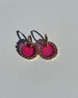Aros colgantes con argolla dorada de acero quirúrgico y dije circular de resina fucsia con borde de strass.